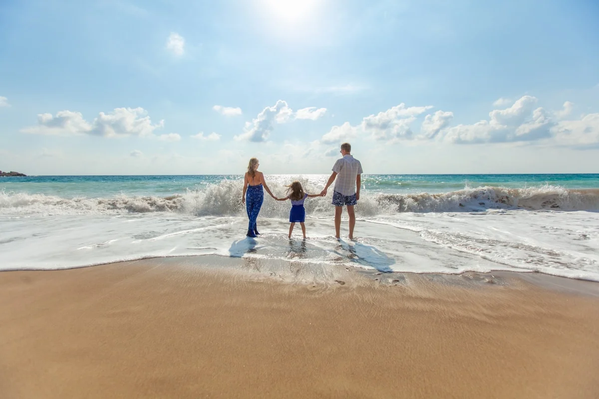 A multi-generational family walking along a private beach at sunset